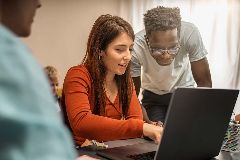 Students using AI essay marking service in University library